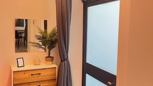 A hallway with a wooden dresser, a potted plant, a mirror, and a frosted glass door. - Residence Diaz (Como)