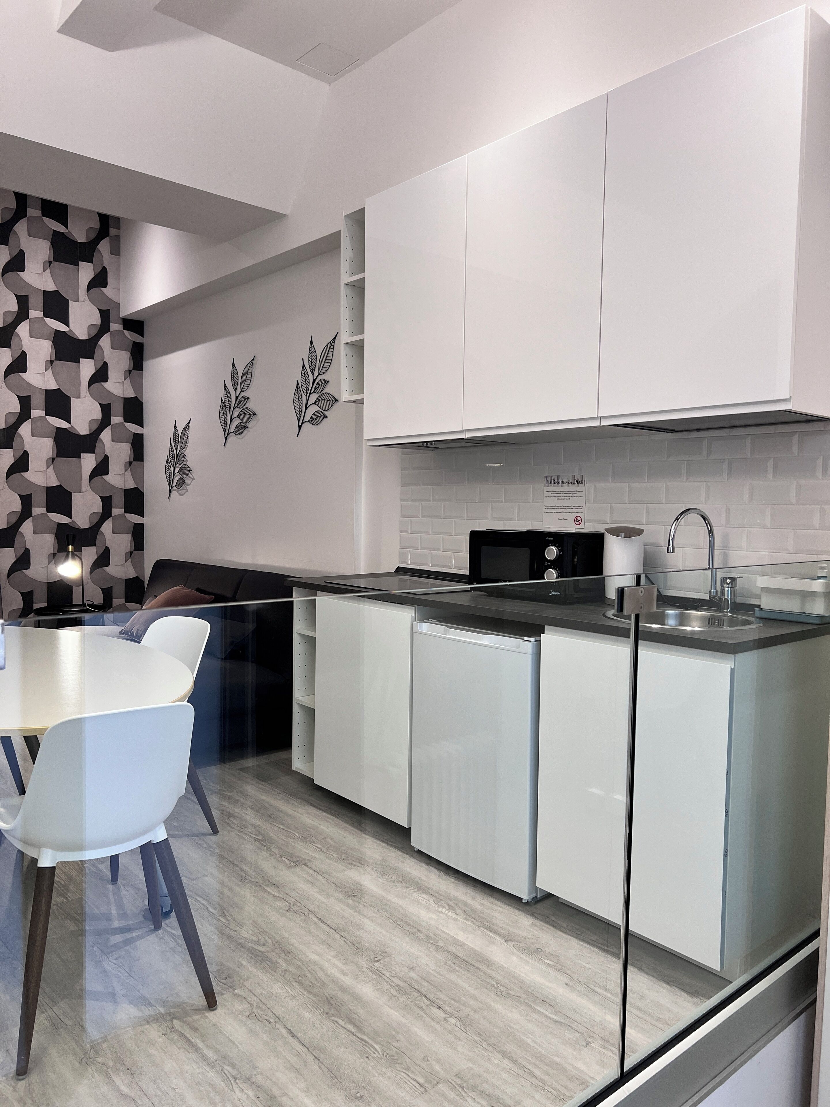 A modern kitchen with white cabinetry, a black countertop, and a dining area with a white table and chairs.