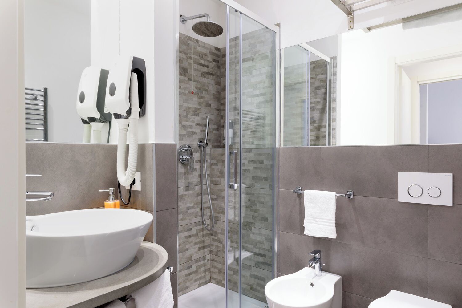 A modern bathroom with a glass-enclosed shower, a large sink, and a small toilet.