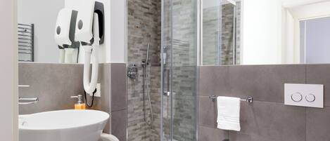 A modern bathroom with a glass-enclosed shower, a large sink, and a small toilet.