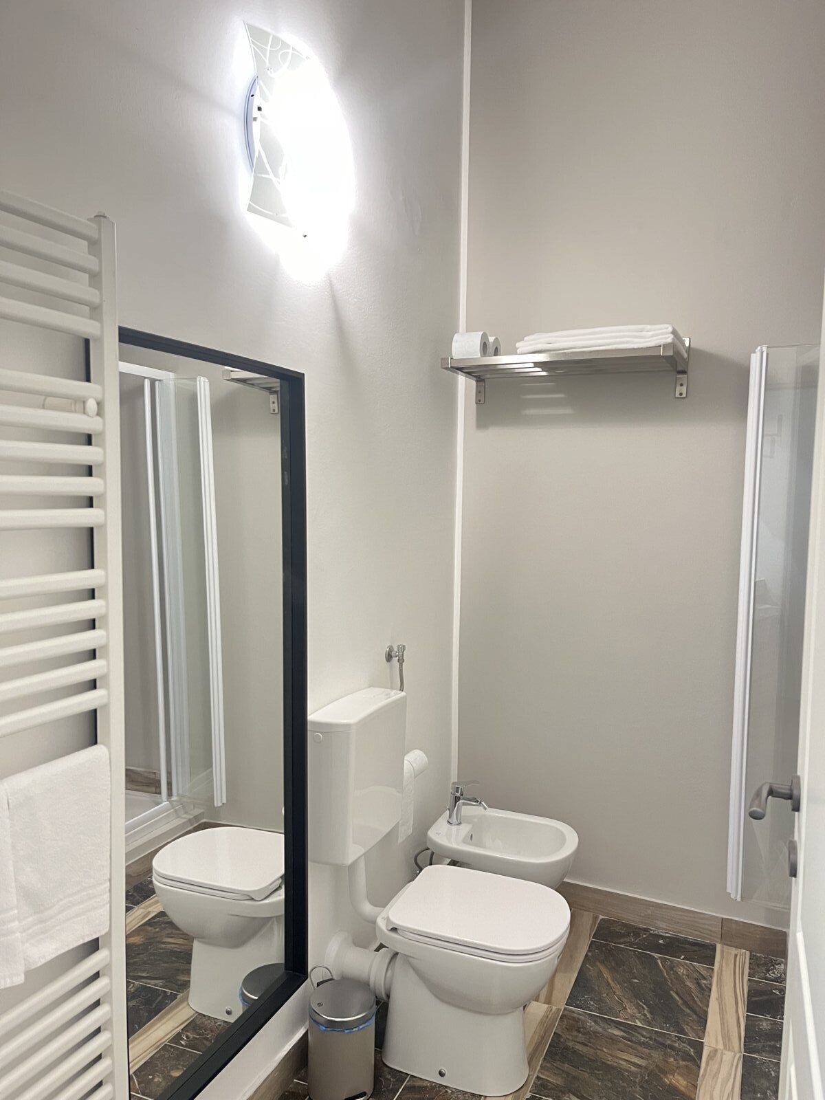 A modern bathroom with a toilet, bidet, and a mirror.