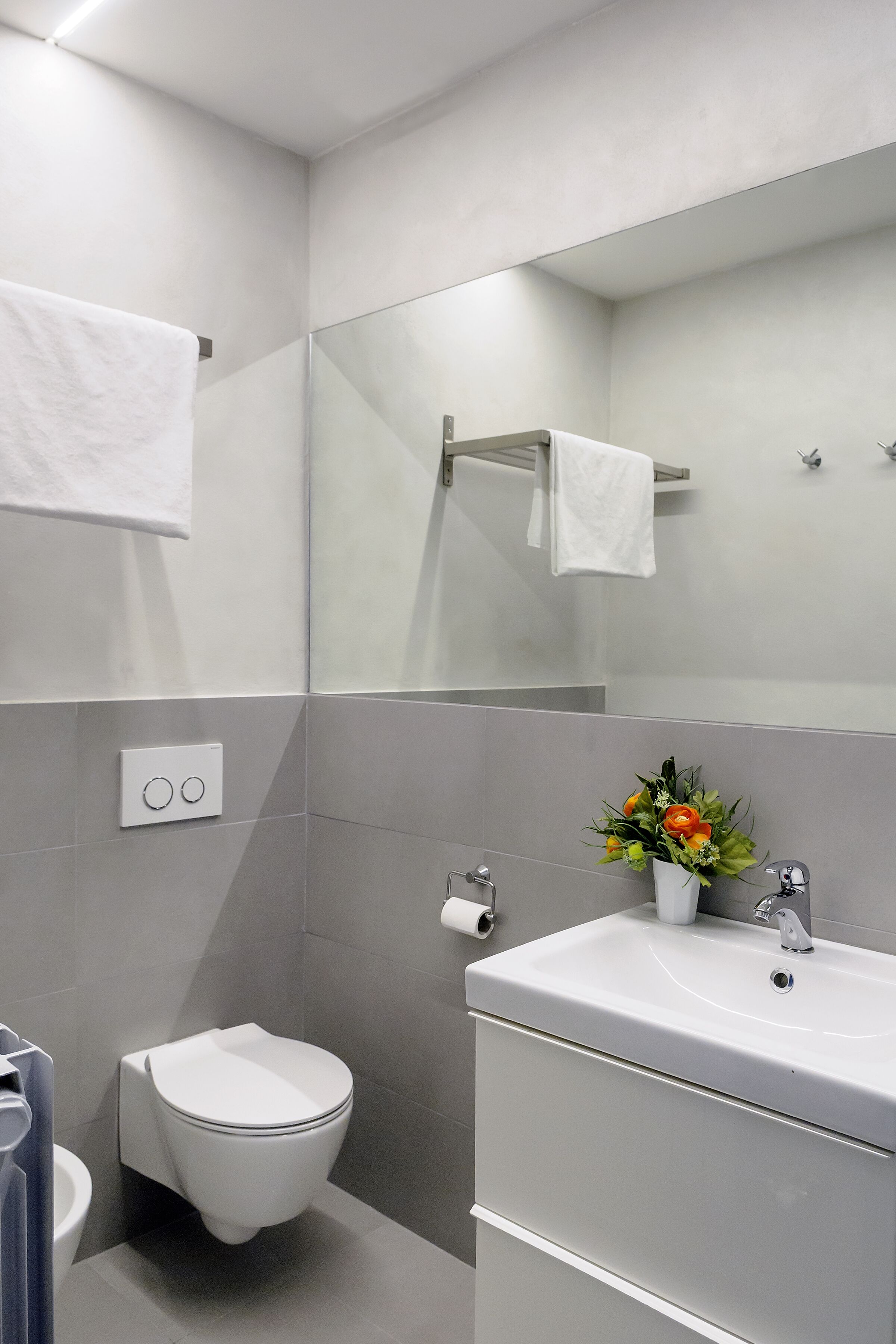 Ein modernes Badezimmer mit Toilette, Waschbecken und Spiegel.