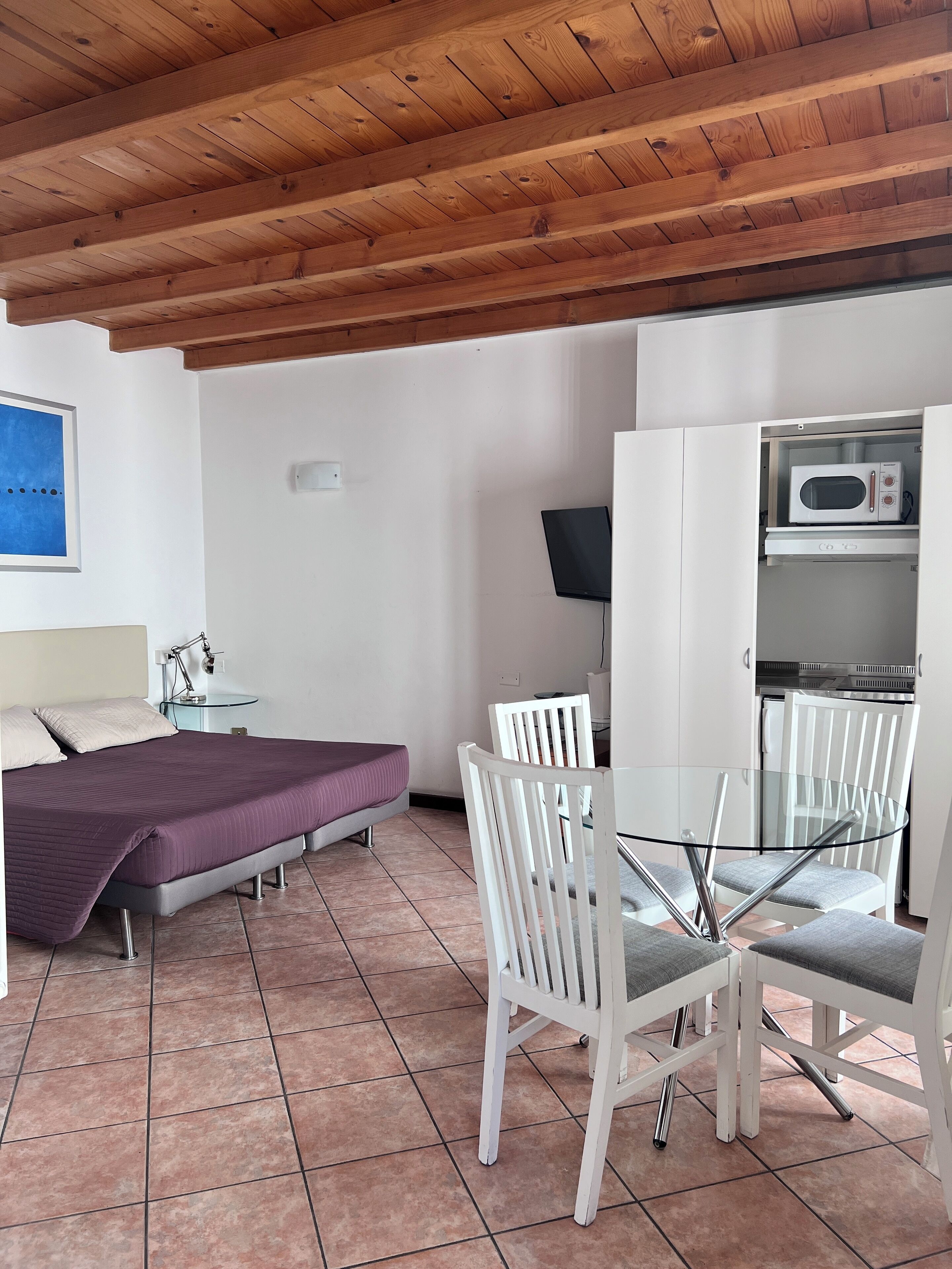 A bedroom with a bed, bedside table, lamp, and a TV.