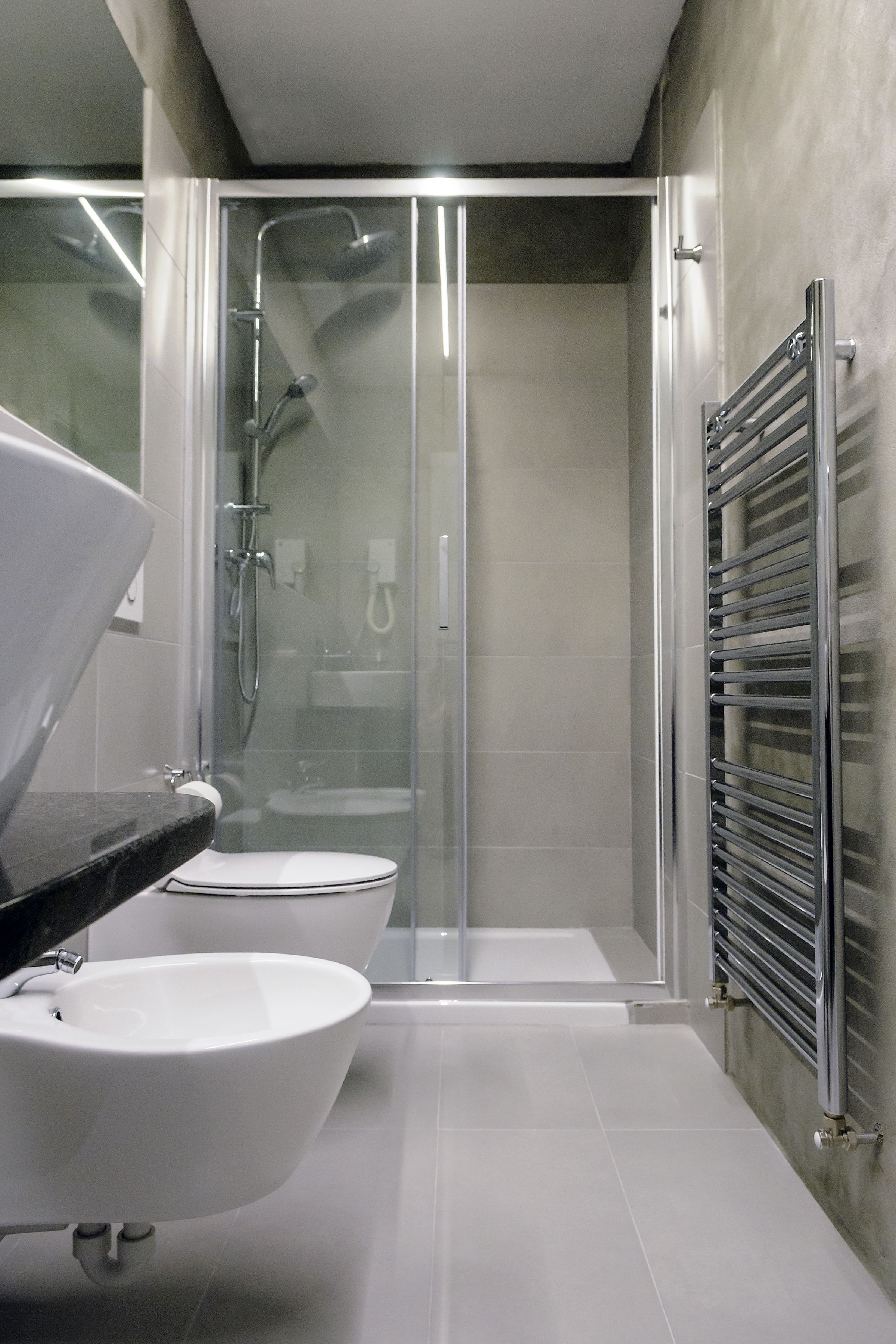 Ein modernes Badezimmer mit einer gläsernen Duschkabine, einem weißen Waschbecken und einem Handtuchhalter.