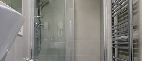A modern bathroom with a glass-enclosed shower, a white sink, and a towel rack.