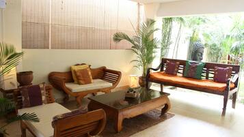 A cozy living area with wooden furniture, a glass coffee table, and a Buddha statue.