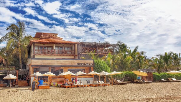 A beachside resort with a bar named 'BARINSTA' and a lounge area with umbrellas. - Don Giovanni Máncora (Máncora)