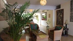 A spacious living room with wicker furniture, a large potted plant, and a traditional artwork on the wall. - Don Giovanni Máncora (Máncora)
