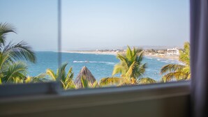 A coastal view with palm trees, a beach, and buildings in the distance. - Don Giovanni Máncora (Máncora)
