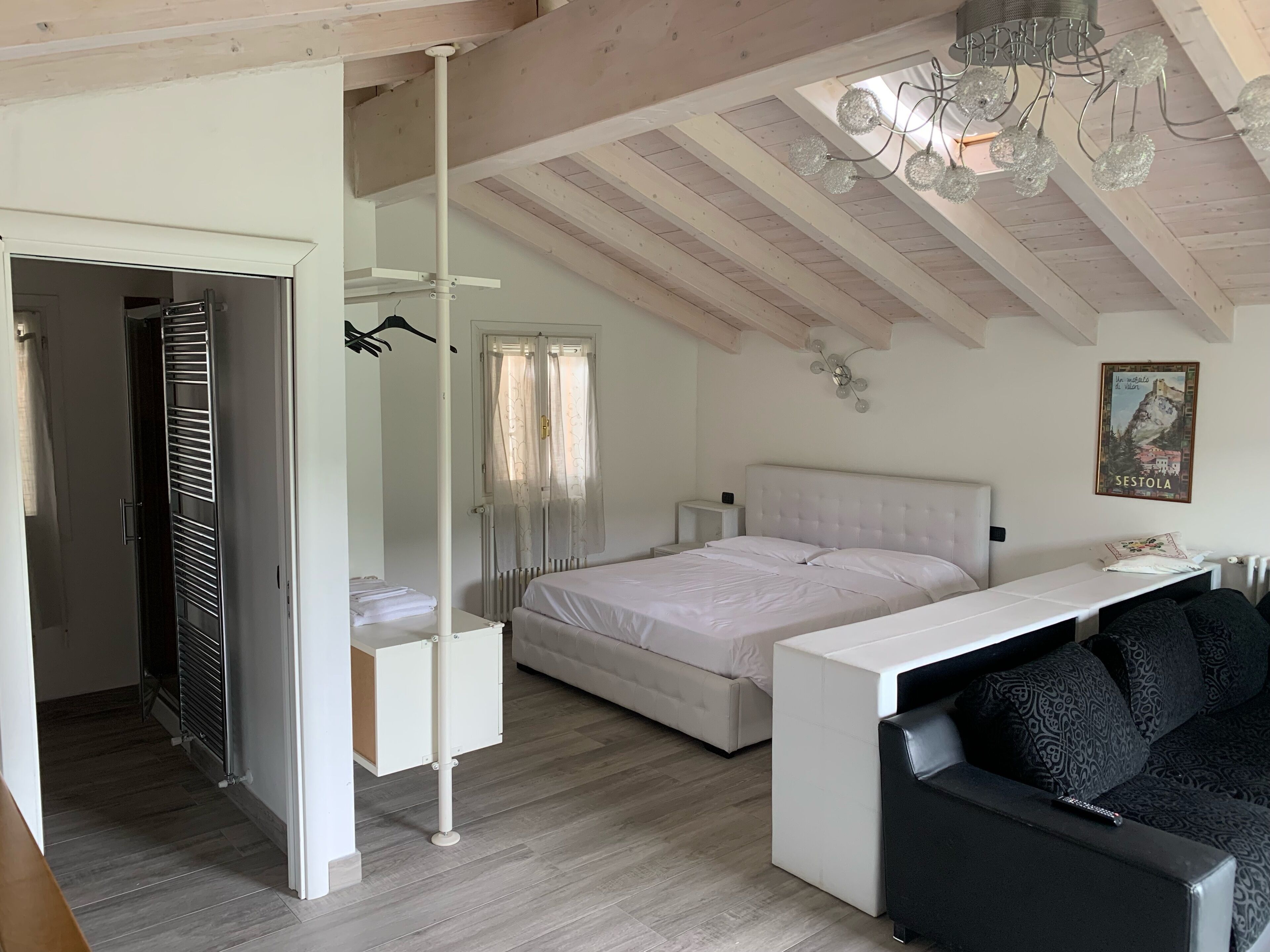 A bedroom with a bed, a desk, a chair, and a hanging light fixture.