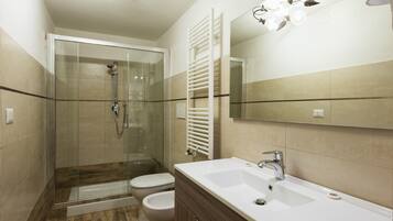 Ein modernes Badezimmer mit einer Duschkabine, einem weißen Waschbecken und einer Toilette.