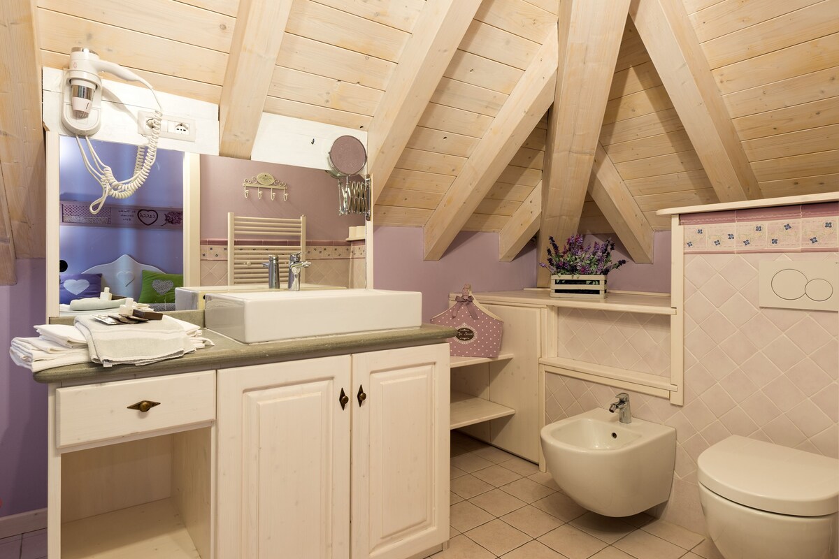 A bathroom with a wooden ceiling, a vanity with a mirror, a bidet, and a toilet.