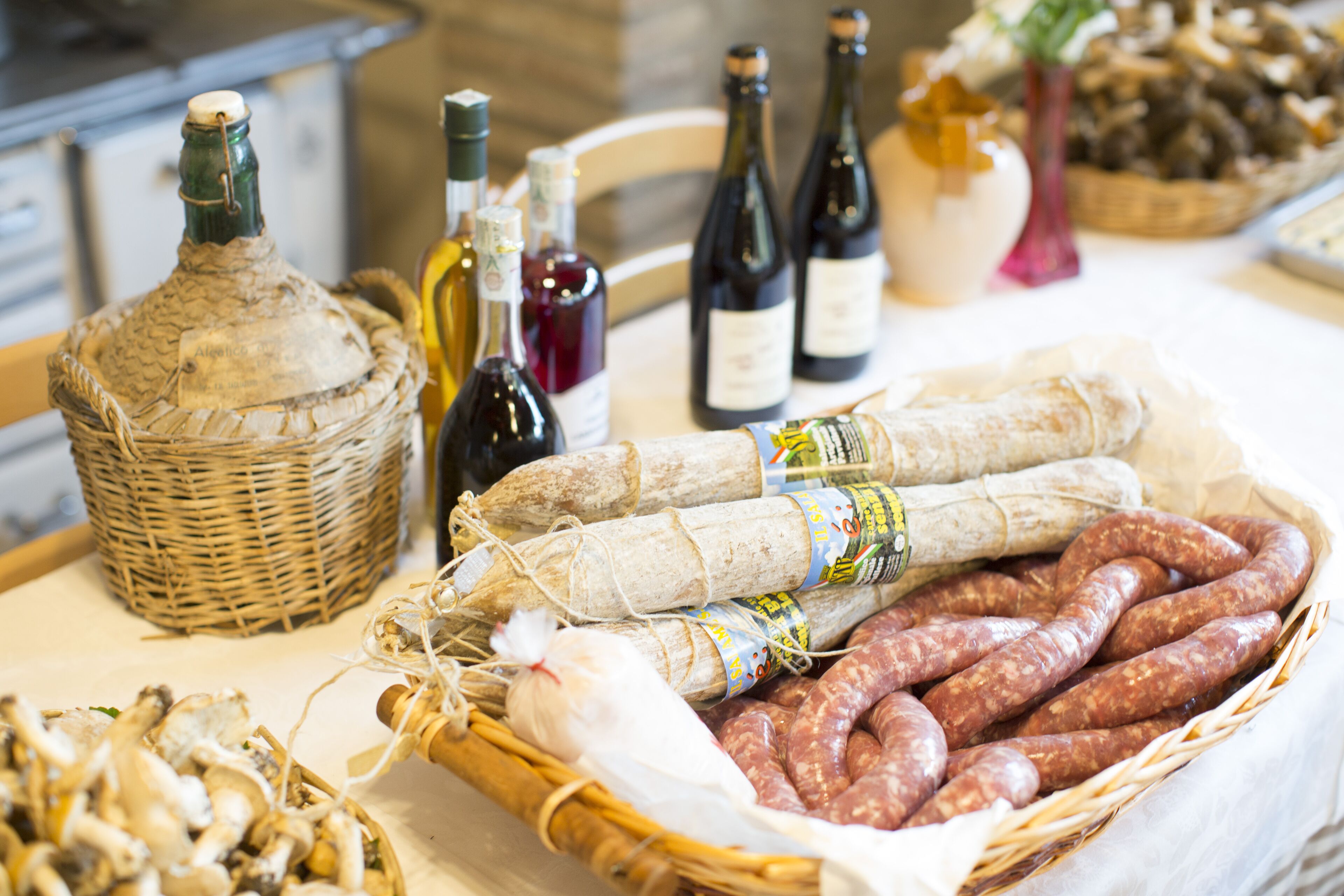Una mesa con diversos alimentos y botellas, entre ellos embutidos, queso y vino.