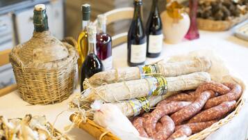 Una mesa con diversos alimentos y botellas, entre ellos embutidos, queso y vino.