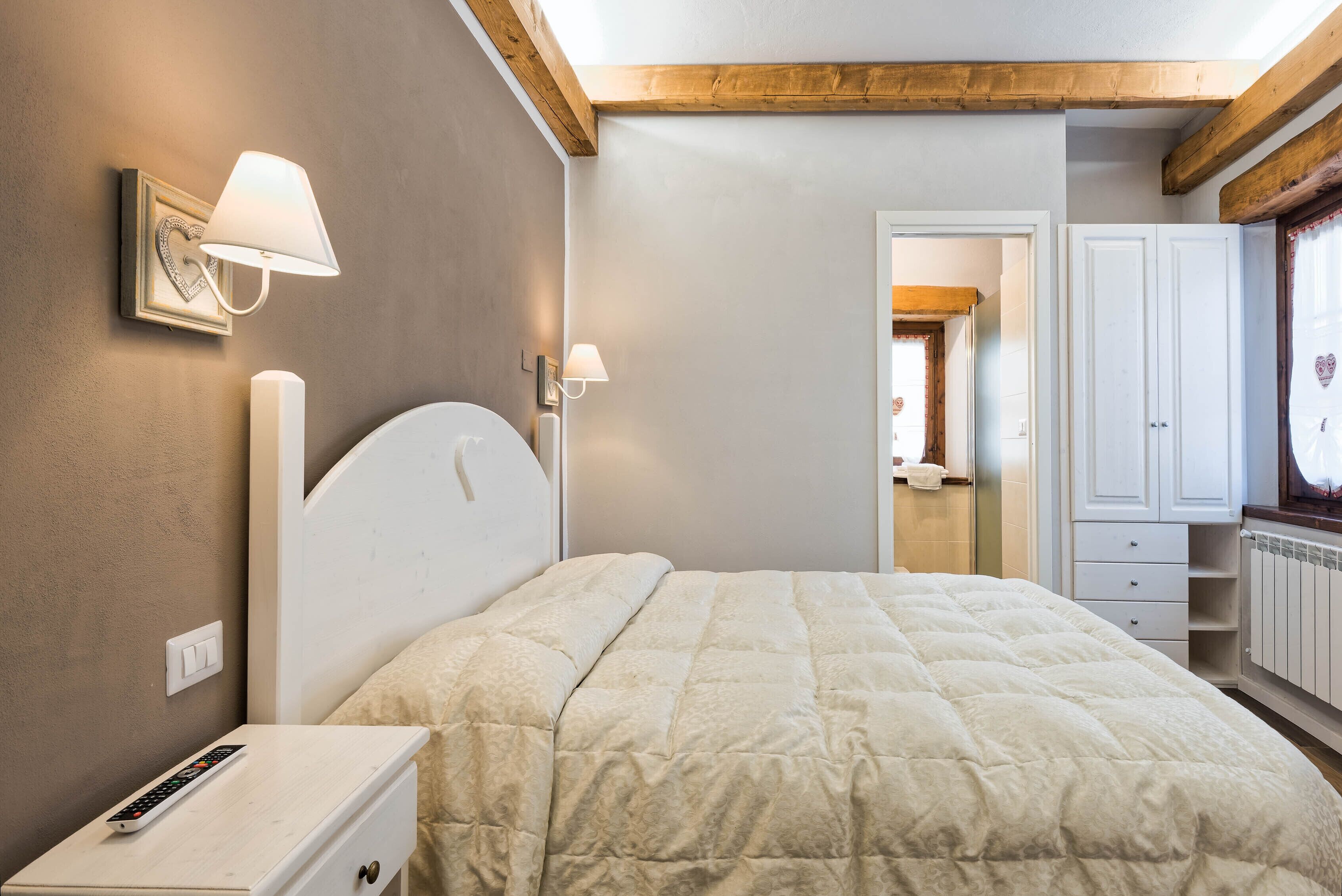 Une chambre à coucher avec un lit, une table de chevet, une lampe et une armoire.