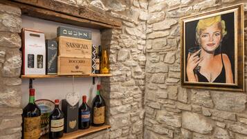Une cave à vin avec des étagères en bois où sont exposées différentes bouteilles et caisses de vin.