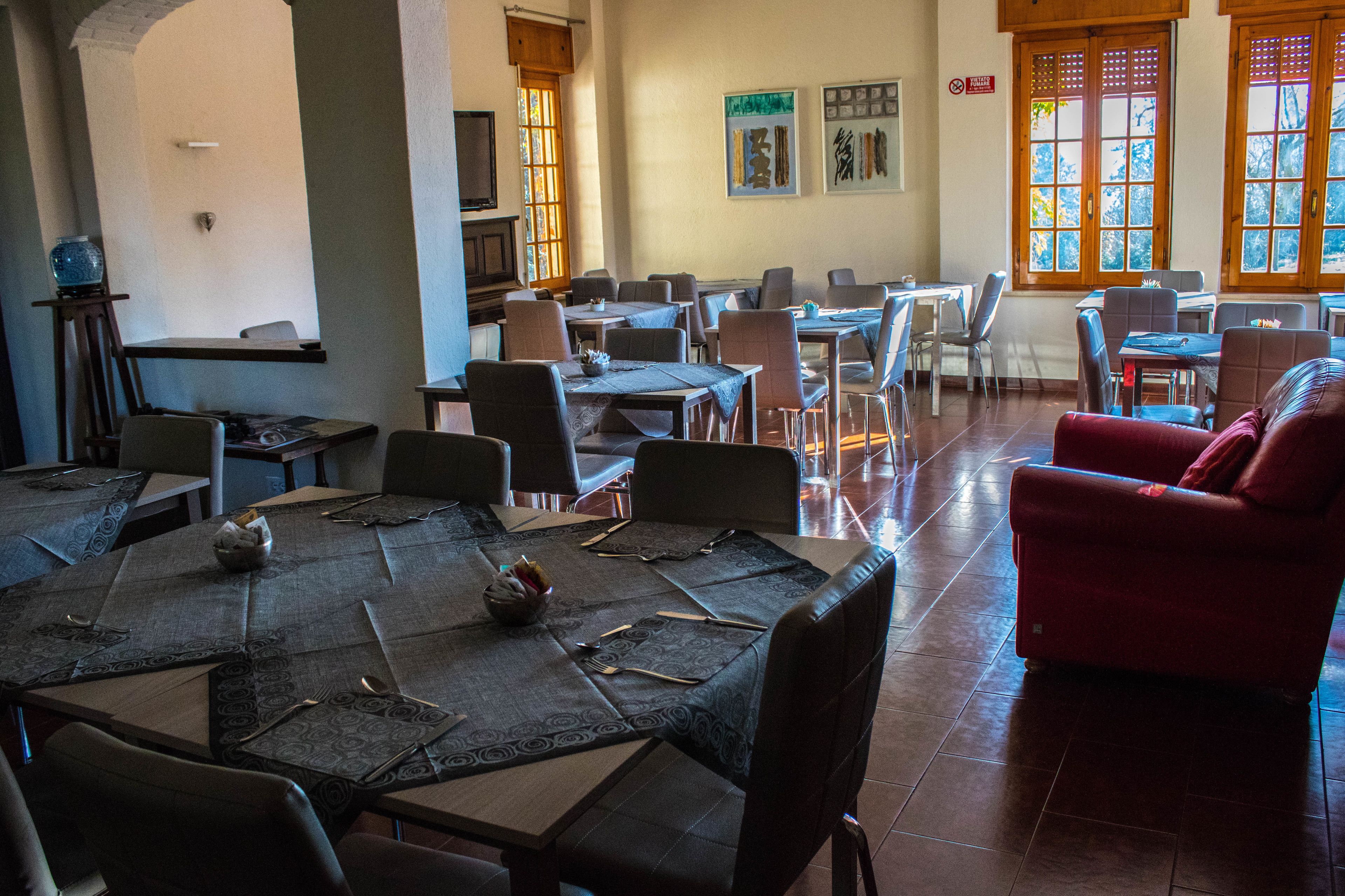 Un espace repas comprenant plusieurs tables et chaises, dont certaines sont recouvertes de nappes et où les couverts sont disposés.