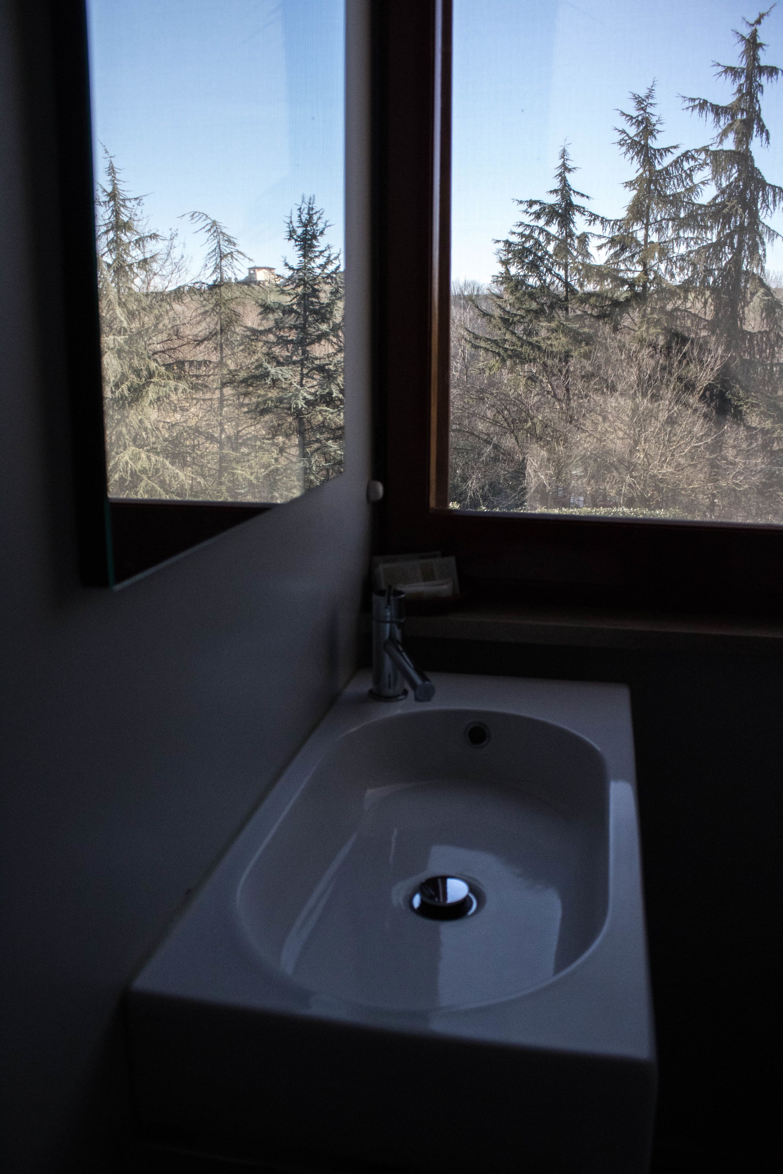 A bathroom with a window, a sink, and a mirror.