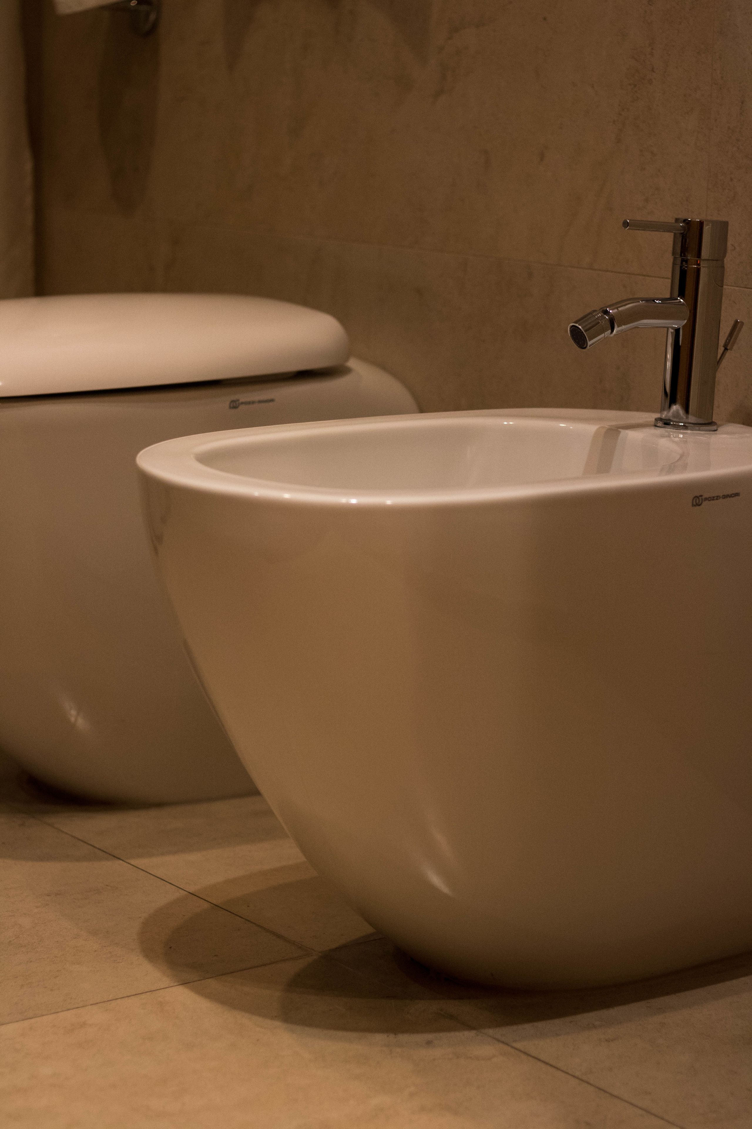 Une salle de bain moderne avec des toilettes blanches et une baignoire sur pieds.