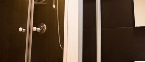 Un baño moderno con cabina de ducha de vidrio, tocador de madera y espejo.