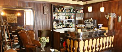 Una zona de bar con paneles de madera, una barra con una caja registradora y estanterías llenas de botellas.