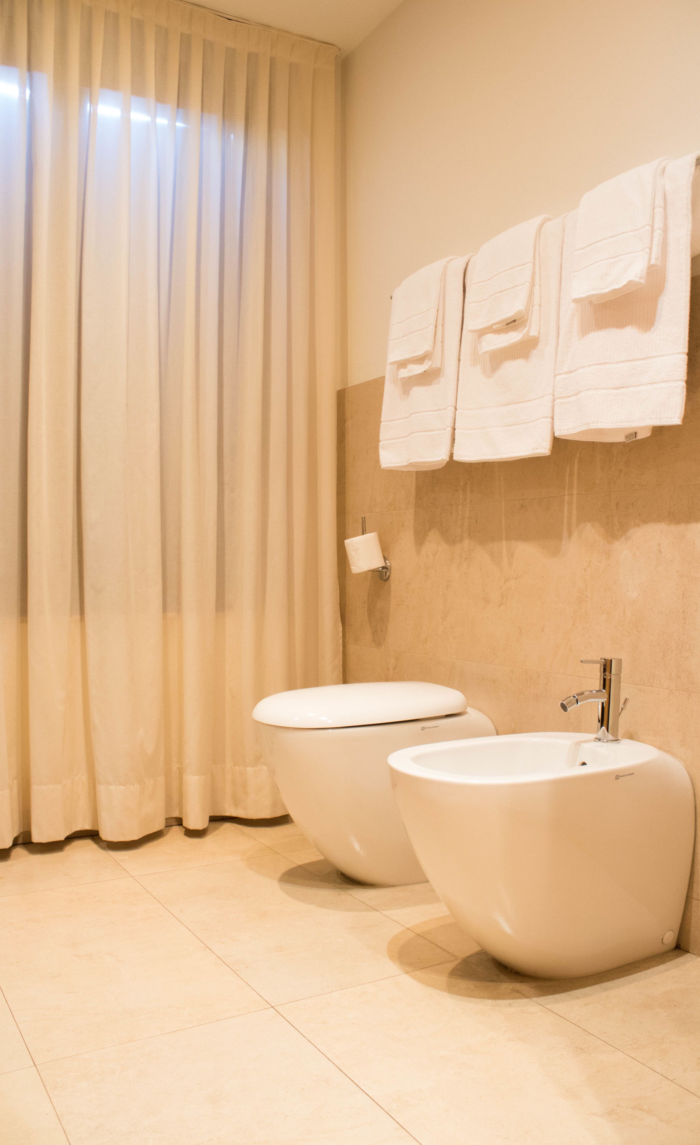 Een badkamer met twee wasbakken, een toilet en een handdoekhouder.