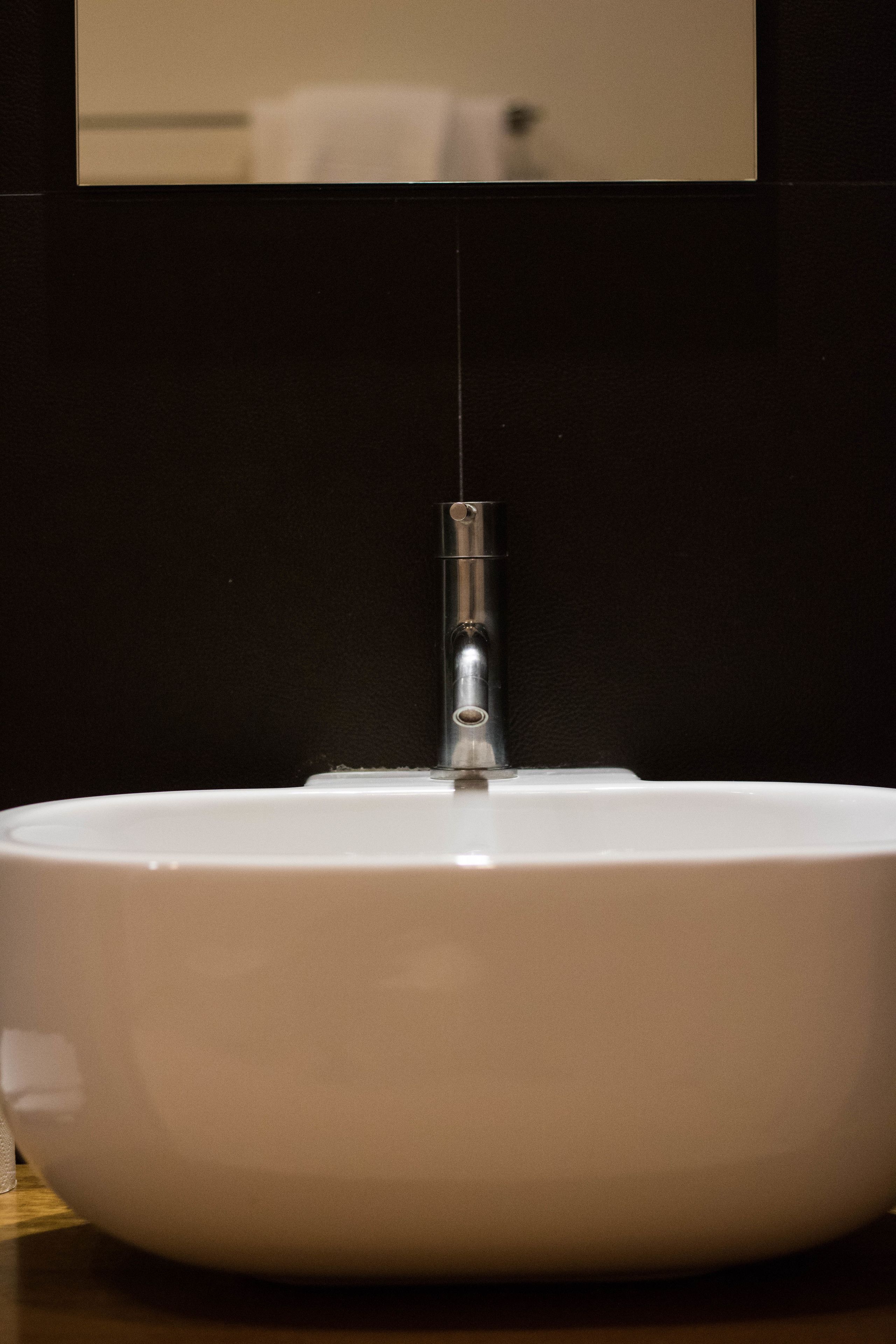A white sink with a faucet and a mirror above it.