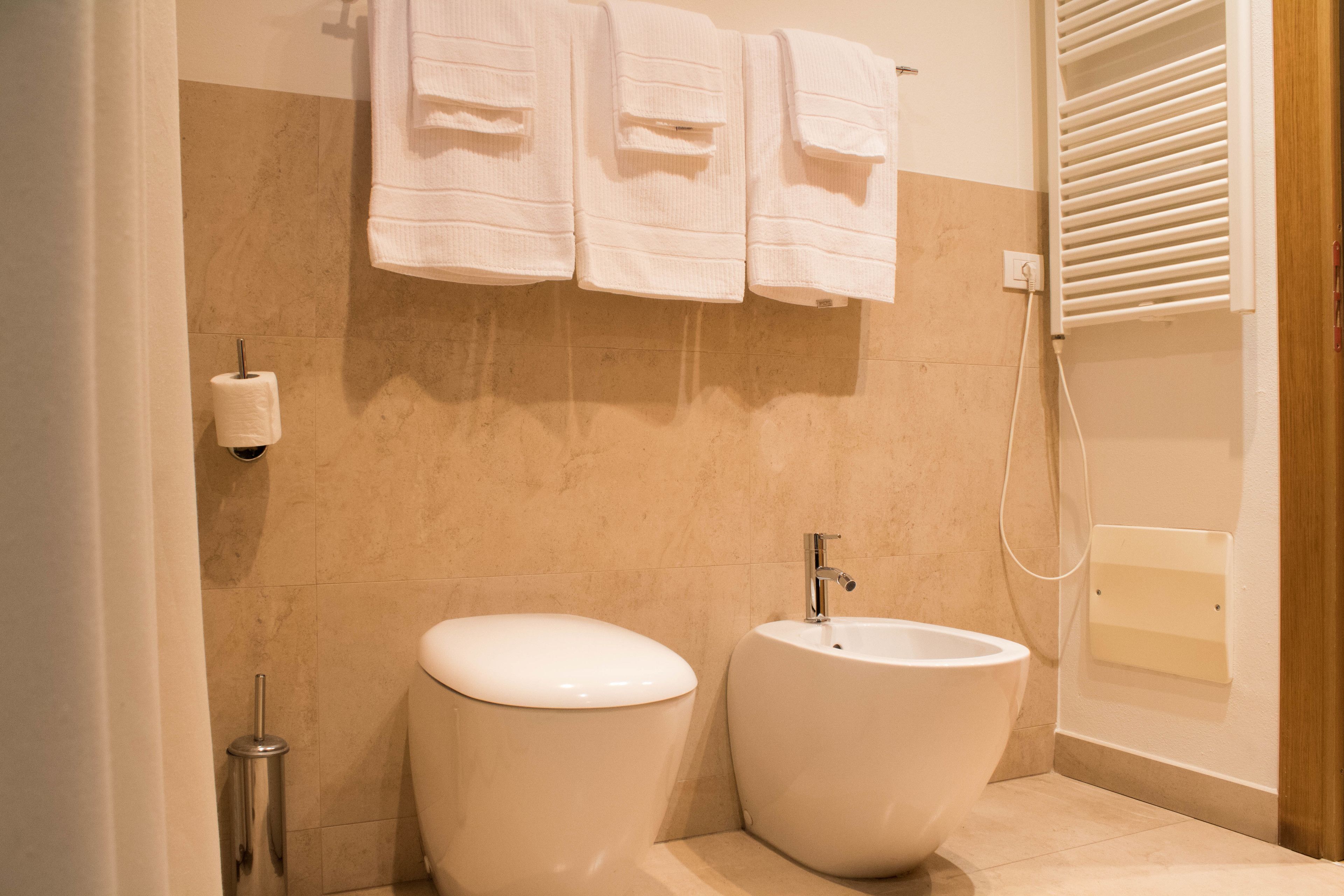 Un baño con inodoro, bidé y toallero.