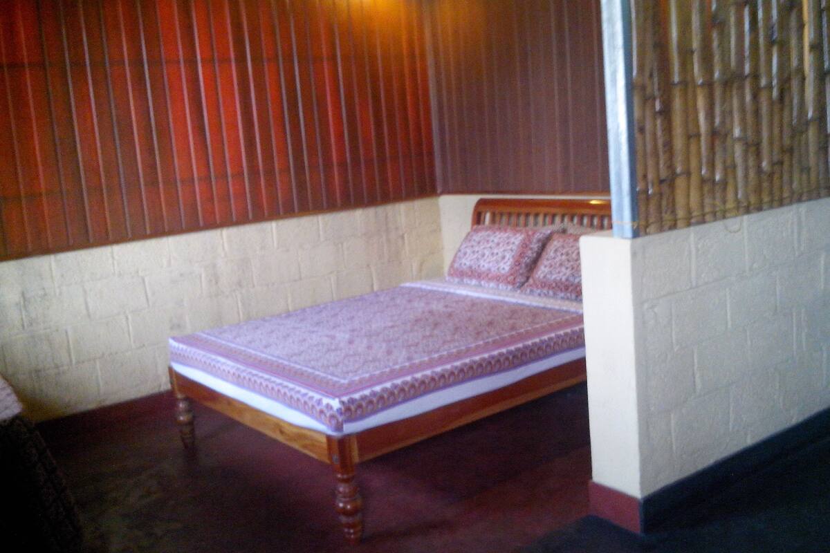 A small, single-bed room with a wooden headboard and a patterned bedspread.