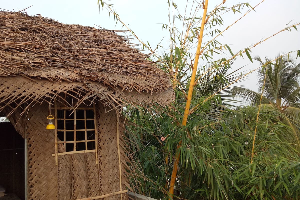 A thatched-roof hut with a small window and a yellow hanging light fixture.