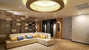 A modern lobby with a sectional sofa, a patterned rug, and a unique circular ceiling light fixture. - Sotetsu Fresa Inn Tokyo Tamachi (Tokyo)