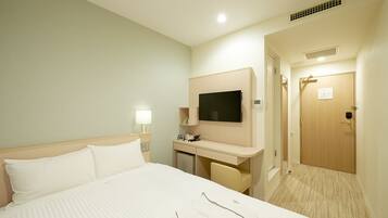 Une chambre d’hôtel avec un lit, un bureau, une télévision et une porte.