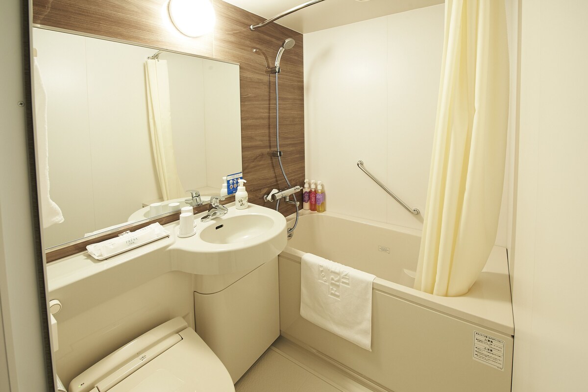 A bathroom with a sink, mirror, shower, and towel rack.