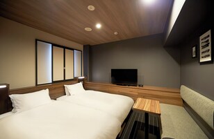Una habitación de hotel con una cama grande, televisión, una mesita y un sofá.