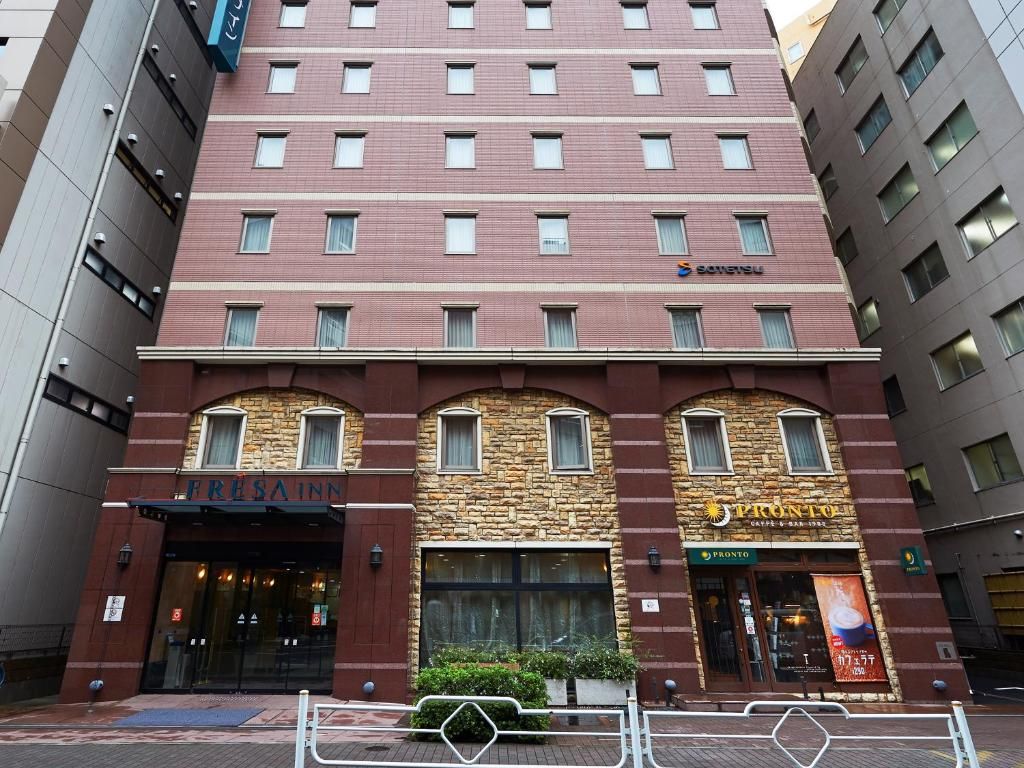 Un hotel de varios pisos con fachada de piedra, dos restaurantes a nivel de calle y una entrada visible.