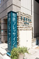 Un edificio de piedra con un letrero que dice 'Fresca Inn' y un letrero vertical con texto en japonés.