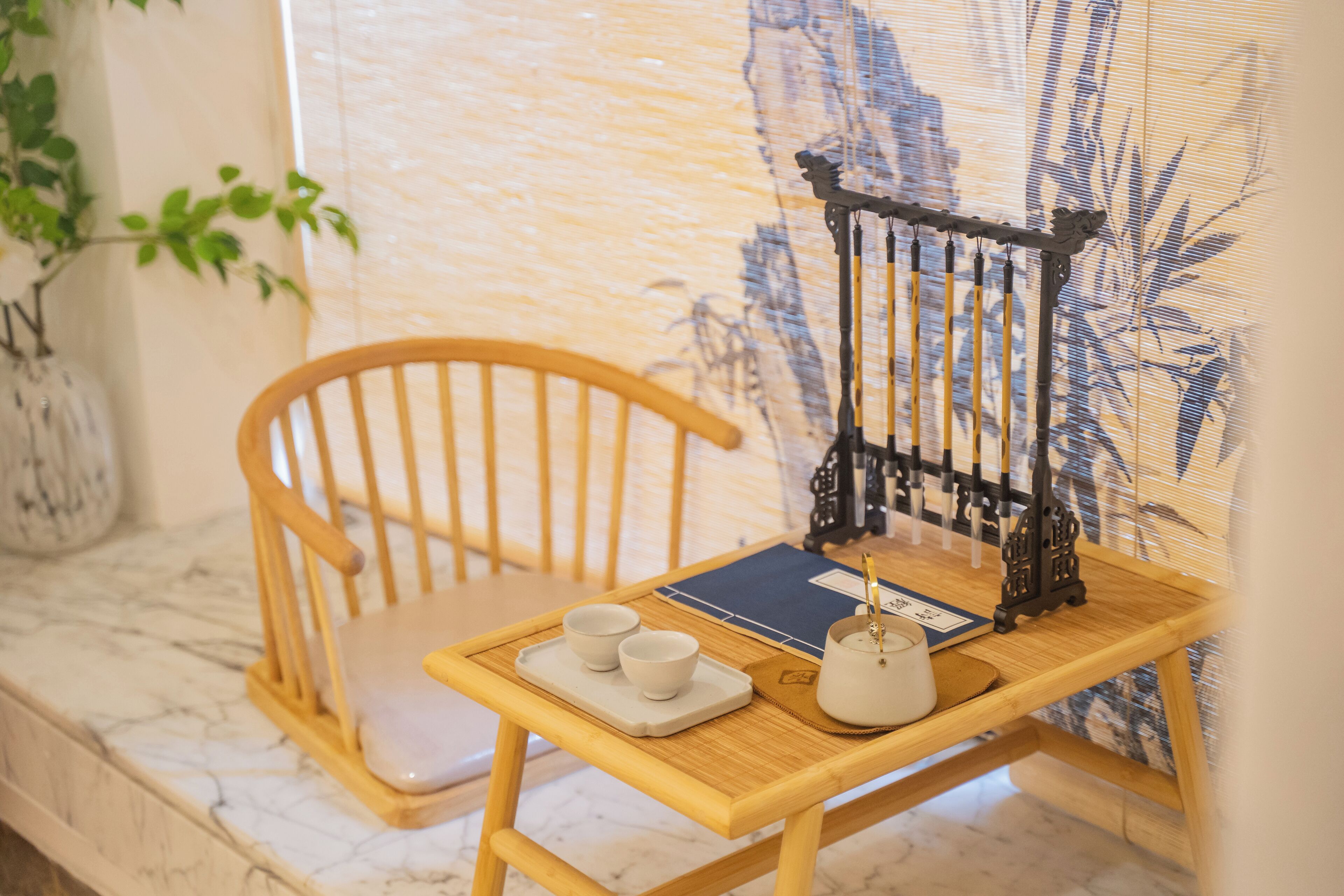 A wooden chair with a tray holding two white cups and a teapot on a table.