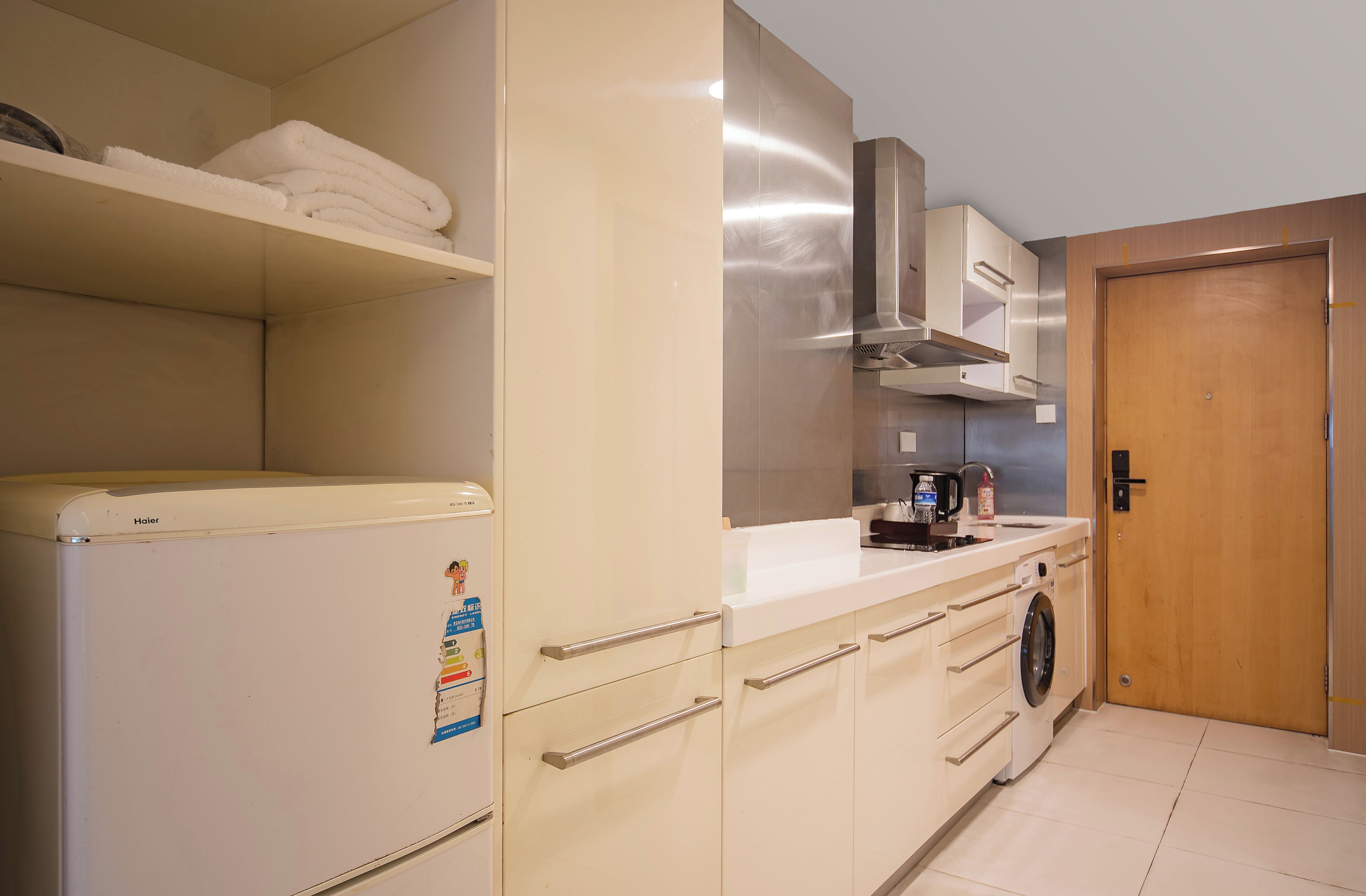 A compact kitchen with a refrigerator, microwave, stove, and a washing machine.