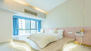 A modern bedroom with a curved bed, a bedside table with a radio, and a view of a building outside. - Lavande International ApartHotel US Consulate General Guangzhou Zhujiang New Town Metro Branch - Free Shuttle Bus to Canton Fair Complex During Canton Fair Period & Free VPN Internet Access (Guangzhou)