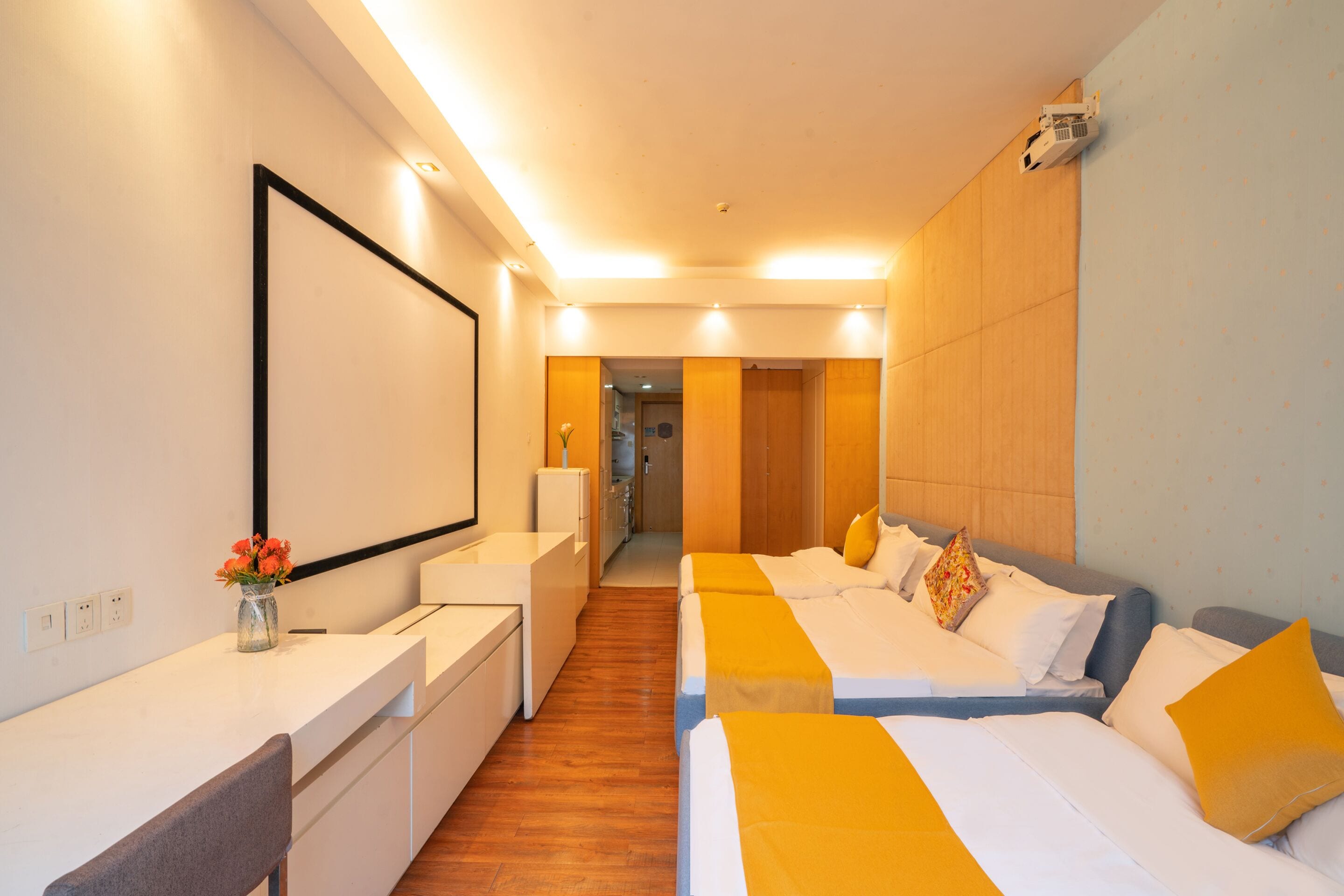 A hotel room with a long corridor, a desk, a chair, and a bed with a headboard.