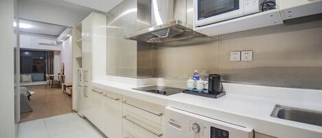 A modern kitchen with a built-in washing machine, microwave, and stainless steel range hood.