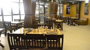 Ein Restaurant mit mehreren Tischen, Stühlen, großen Fenstern und Bildern an den Wänden.