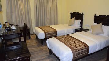 A hotel room with two beds, a desk, and a chair.