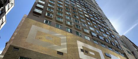 A high-rise building with a modern architectural design, featuring a prominent geometric pattern on the facade and numerous windows.