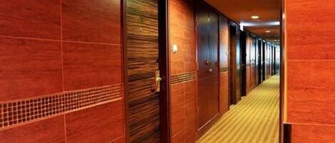 A hotel corridor with wooden doors and a carpeted floor.
