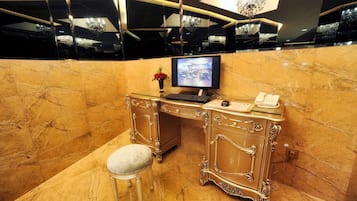 A luxurious marble desk with a computer, a telephone, and a vase with a red flower.