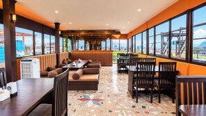 A restaurant with a high ceiling, large windows, and a mix of seating including tables and booths. - Hotel Nepalaya (Kathmandu)