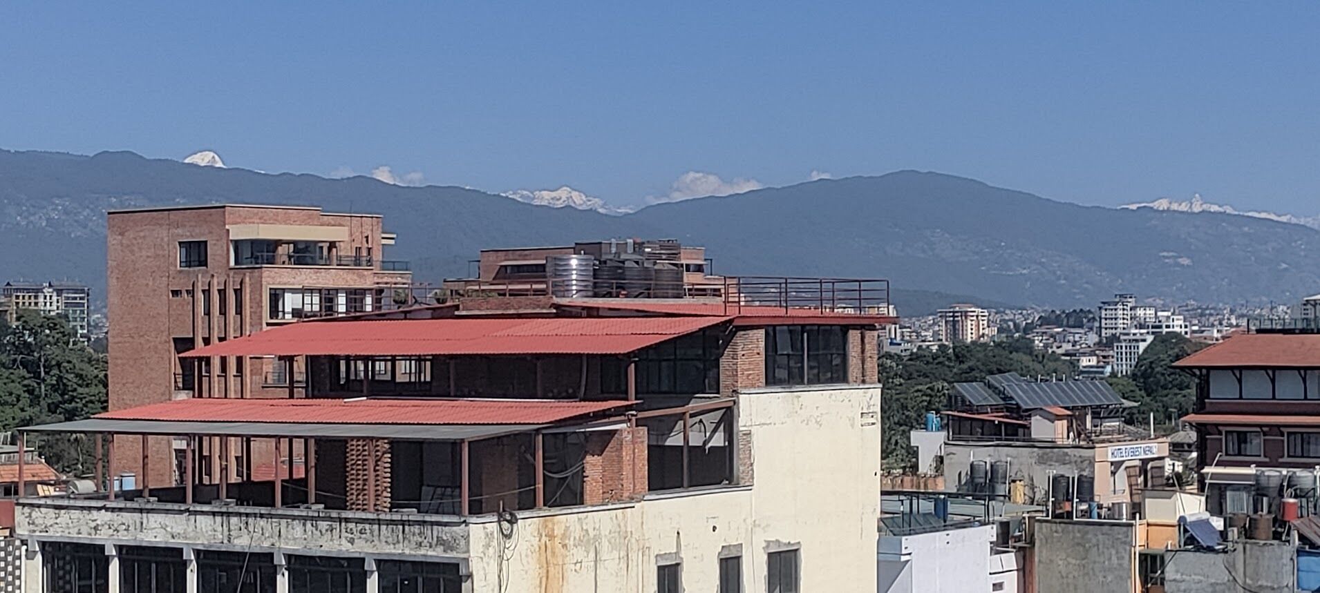 Un edificio de varios pisos con techo rojo, tanque de agua visible y un letrero que indica un hotel.