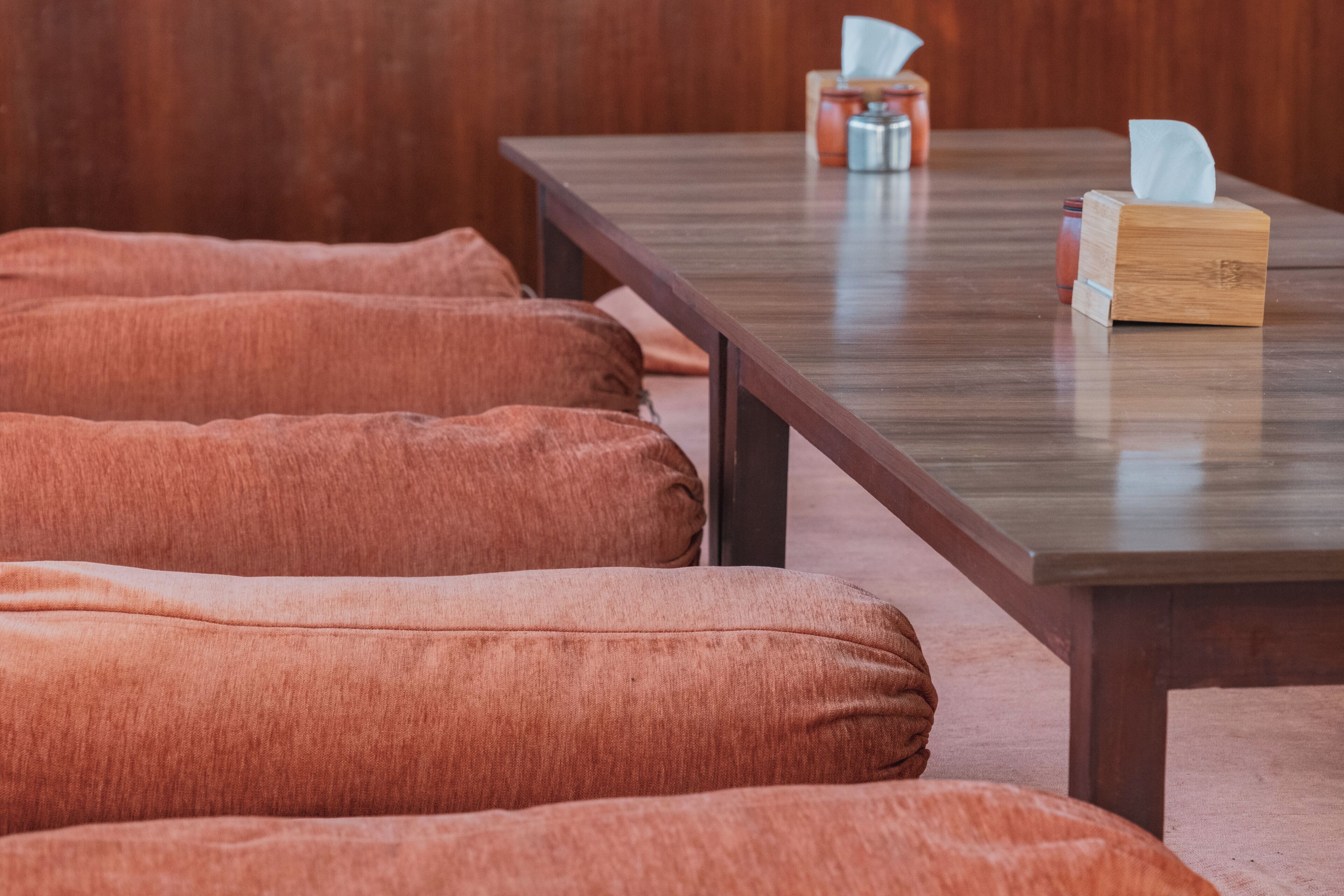 Una mesa de madera con una caja de pañuelos y un dispensador.