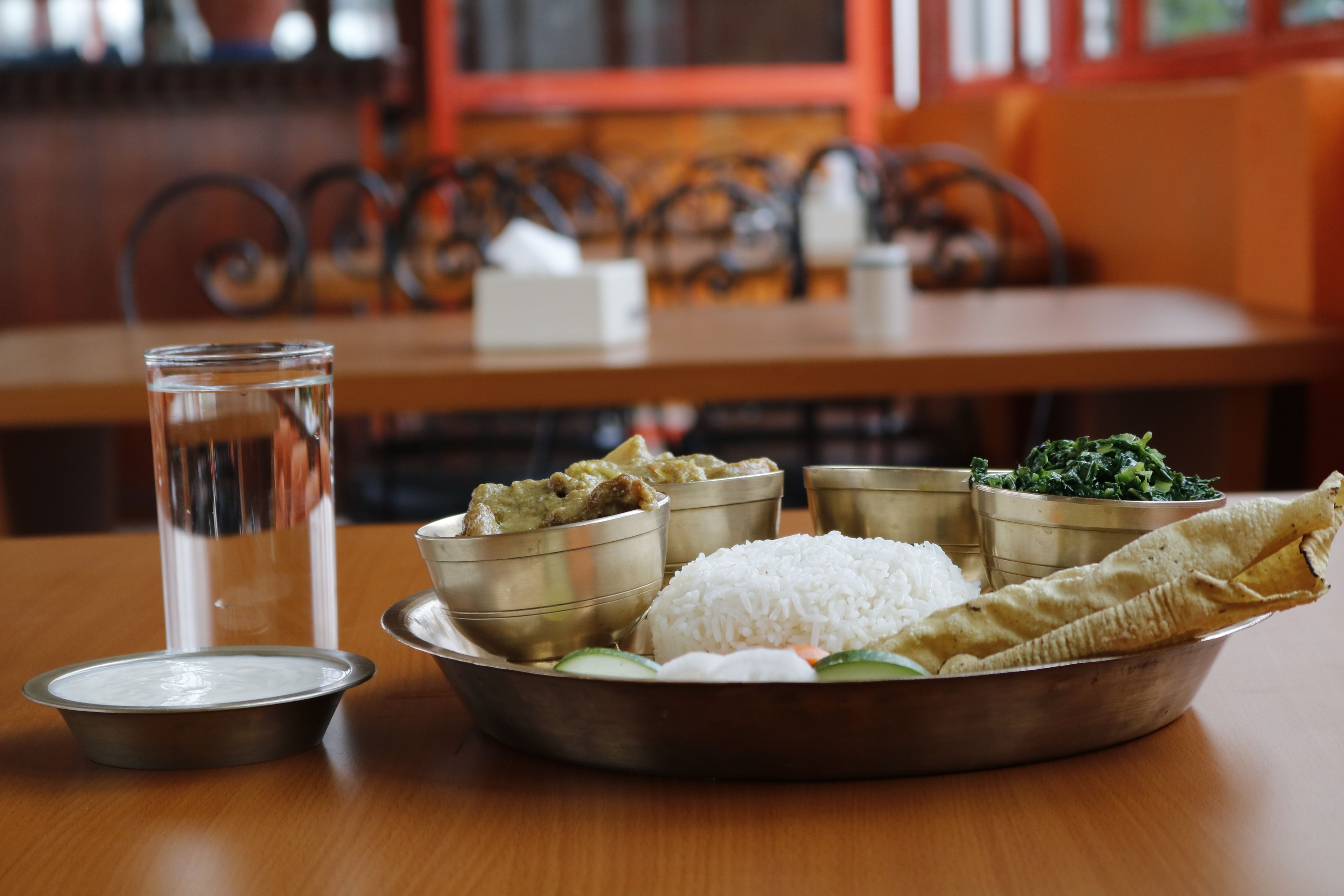 Un repas composé de riz, de légumes et servi sur une feuille de bananier, le tout présenté sur une table.